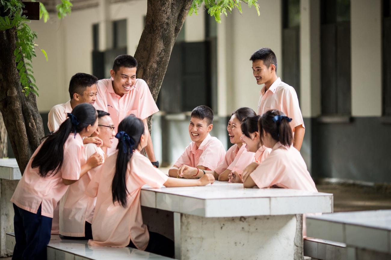 A group of young children in an outdoor setting, sitting around a table