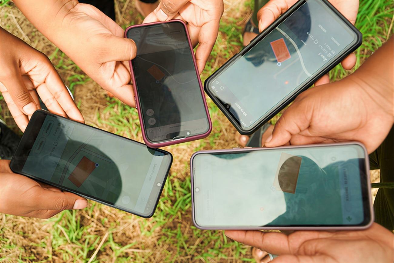 Several hands each hold a cell phone.