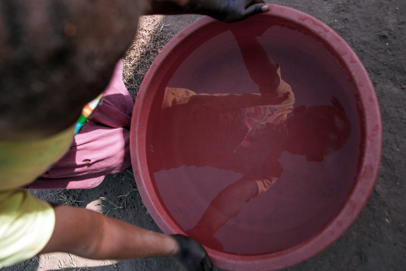 A child in South Sudan looks at his reflection in a bucket of water.