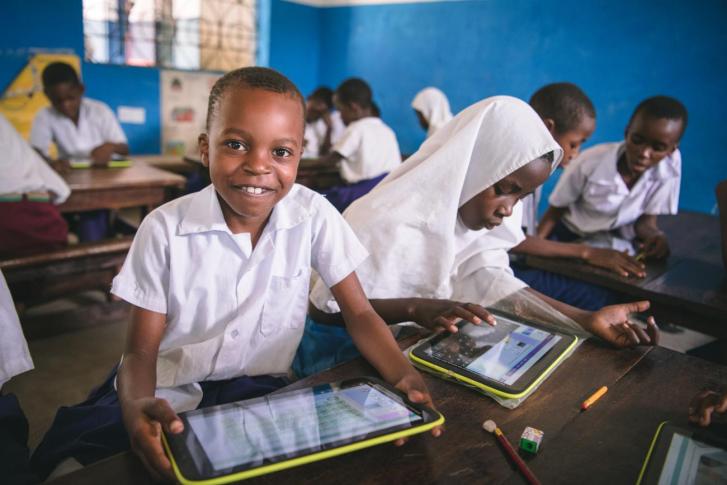 Kenyan elementary school students (male and female) using tablets in a classroom.