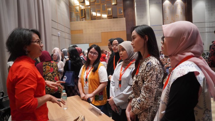 A woman leader in Indonesia talks to young women at an event.