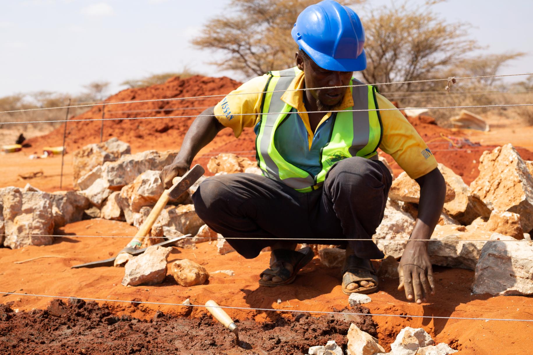 construction worker in hard hat measures the foundation of a wall