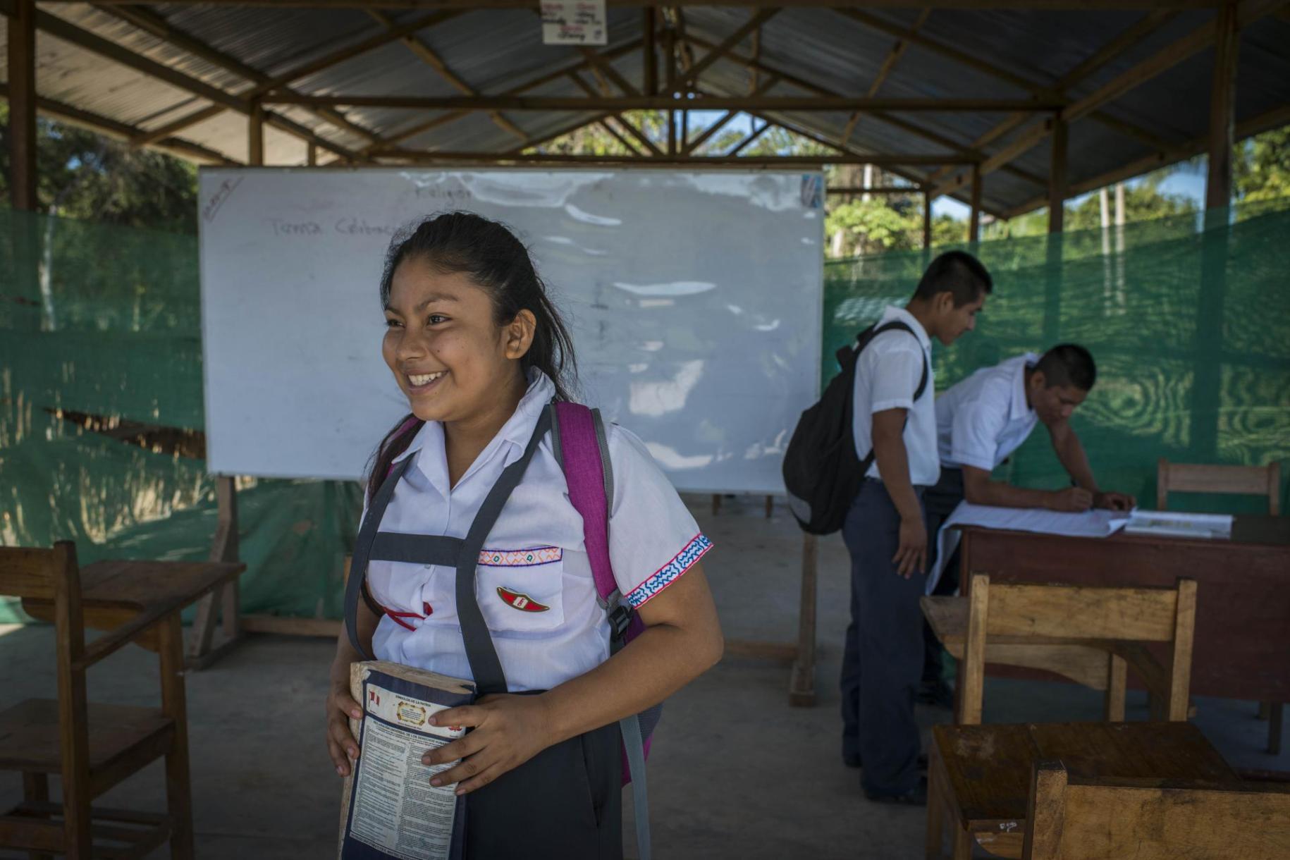 young school girl with backpack walks towards the camera smiling