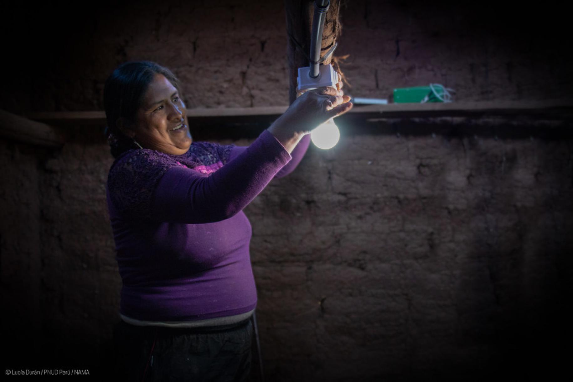 woman in purple top changes lightbulb