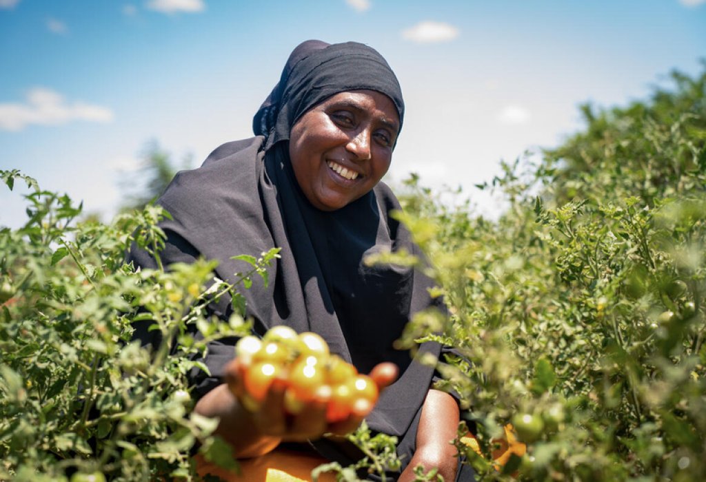 Woman holding a fruit and smiling.